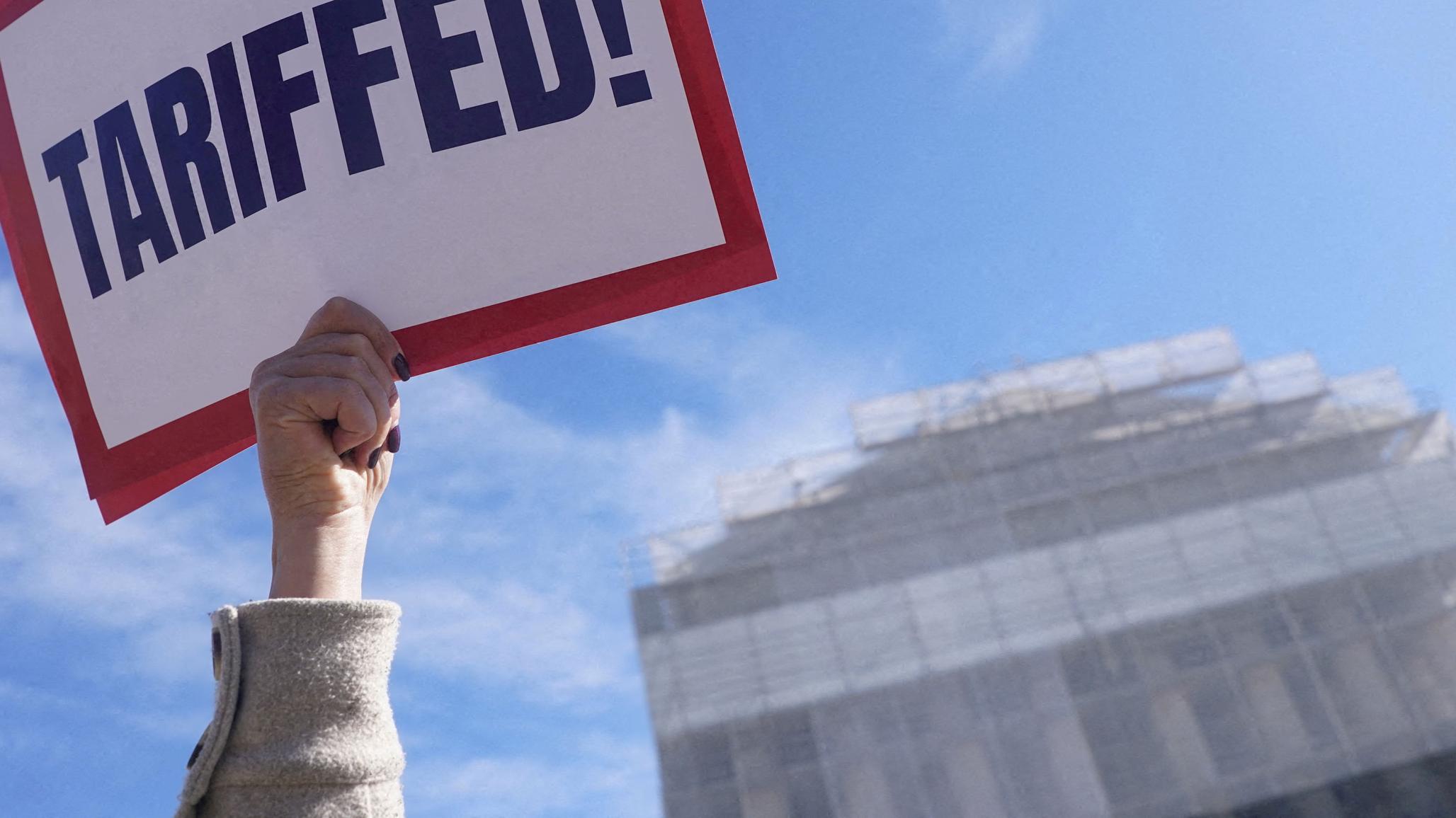 A protester against Trump’s tariffs holds a sign outside the US Supreme Court, as its justices are set to hear oral arguments on the President’s bid to preserve sweeping tariffs, in Washington, DC. Picture taken on November 5, 2025. 
