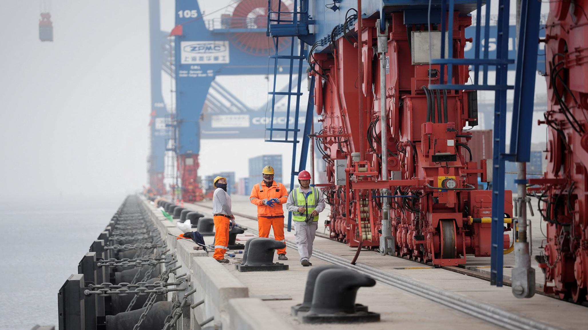 Workers stand on a platform at Peru’s Port of Chancay, built by China's state-owned Cosco Shipping to be a hub for shipping lithium and other critical minerals from South America to China. Picture taken on October 24, 2024. 
