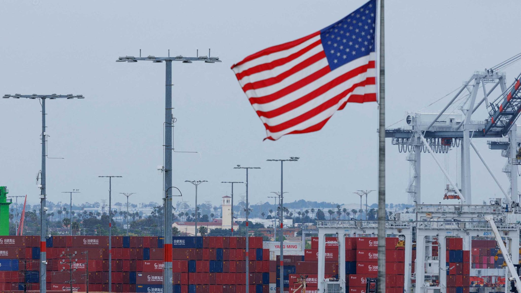 A US flag flutters near shipping containers at the Port of Los Angeles in California, May 2025. 