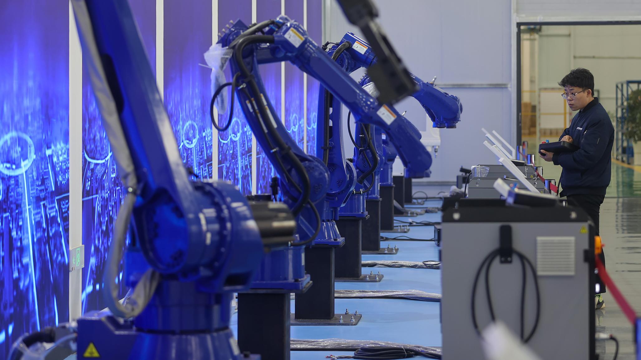 A technician works on robotic arms in a manufacturing plant in China. Photo taken on March 12, 2026.