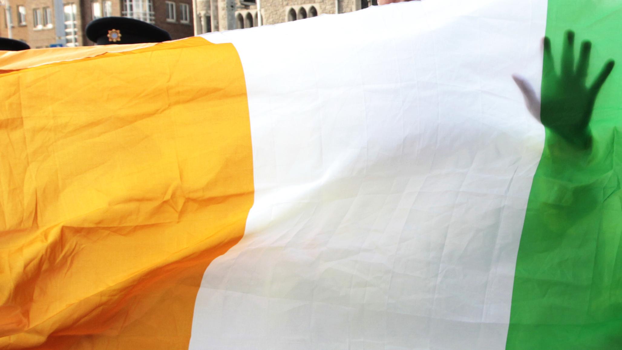 An Irish police officer stands in front of an Irish flag in Dublin, Ireland. 