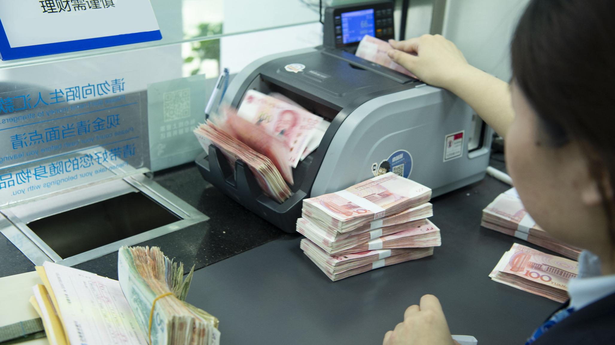 A bank teller counts renminbi at a retail bank in China where deposits are covered by China’s deposit insurance fund. July 2024. 