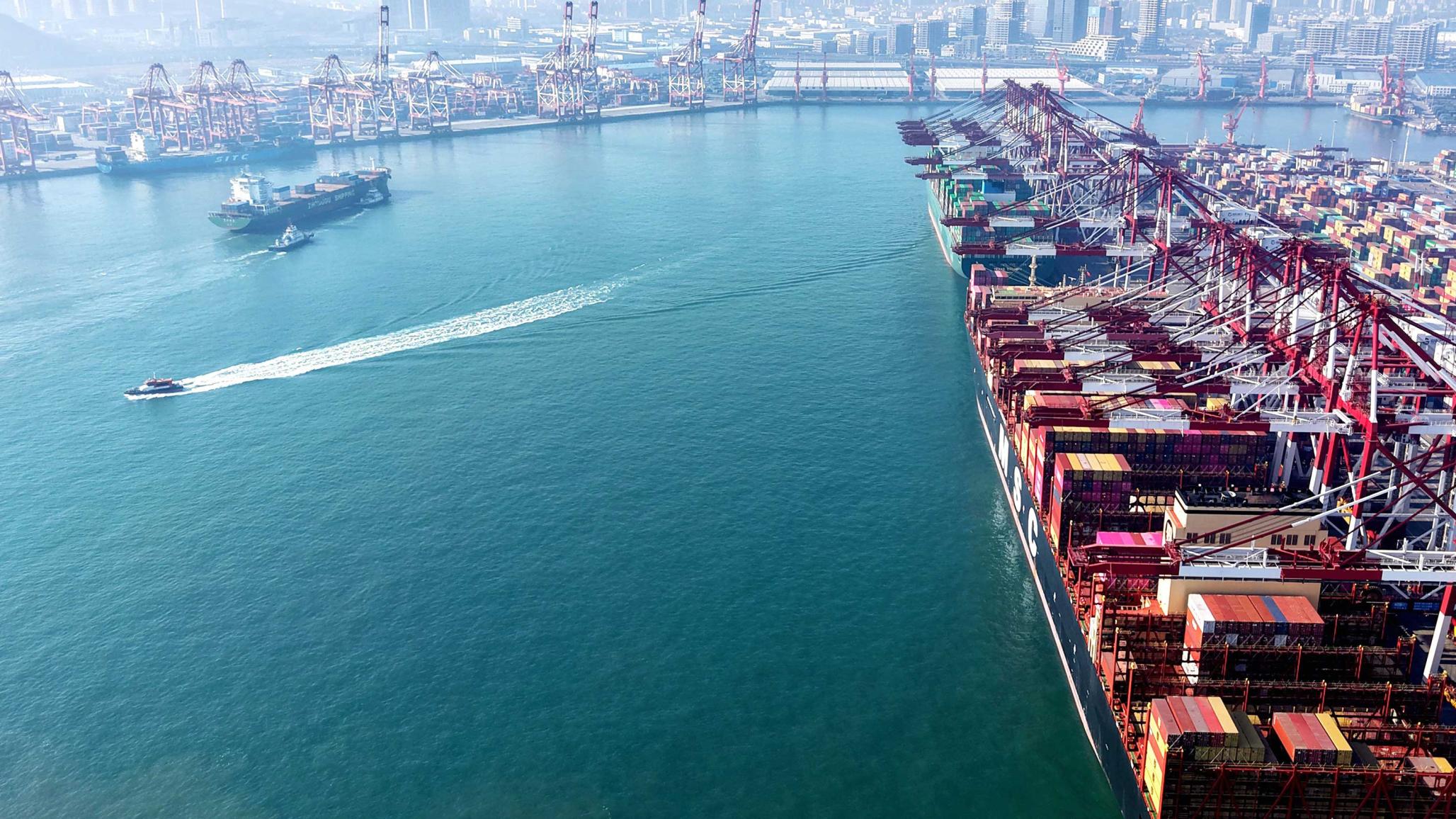 A cargo ship being directed by tugboats, at a port in Asia. February 2026. 