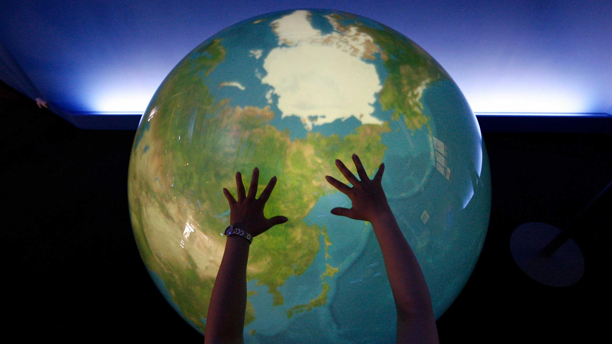 A visitor places her hands on a "Tangible Earth" at an exhibition pavilion on Japan's northern island of Hokkaido. July 6, 2008. 