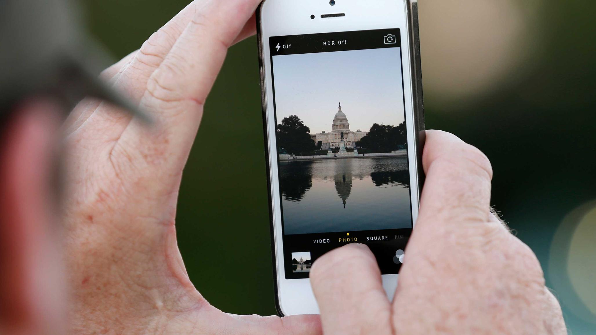 A man takes a photo of the U.S. Capitol. 
