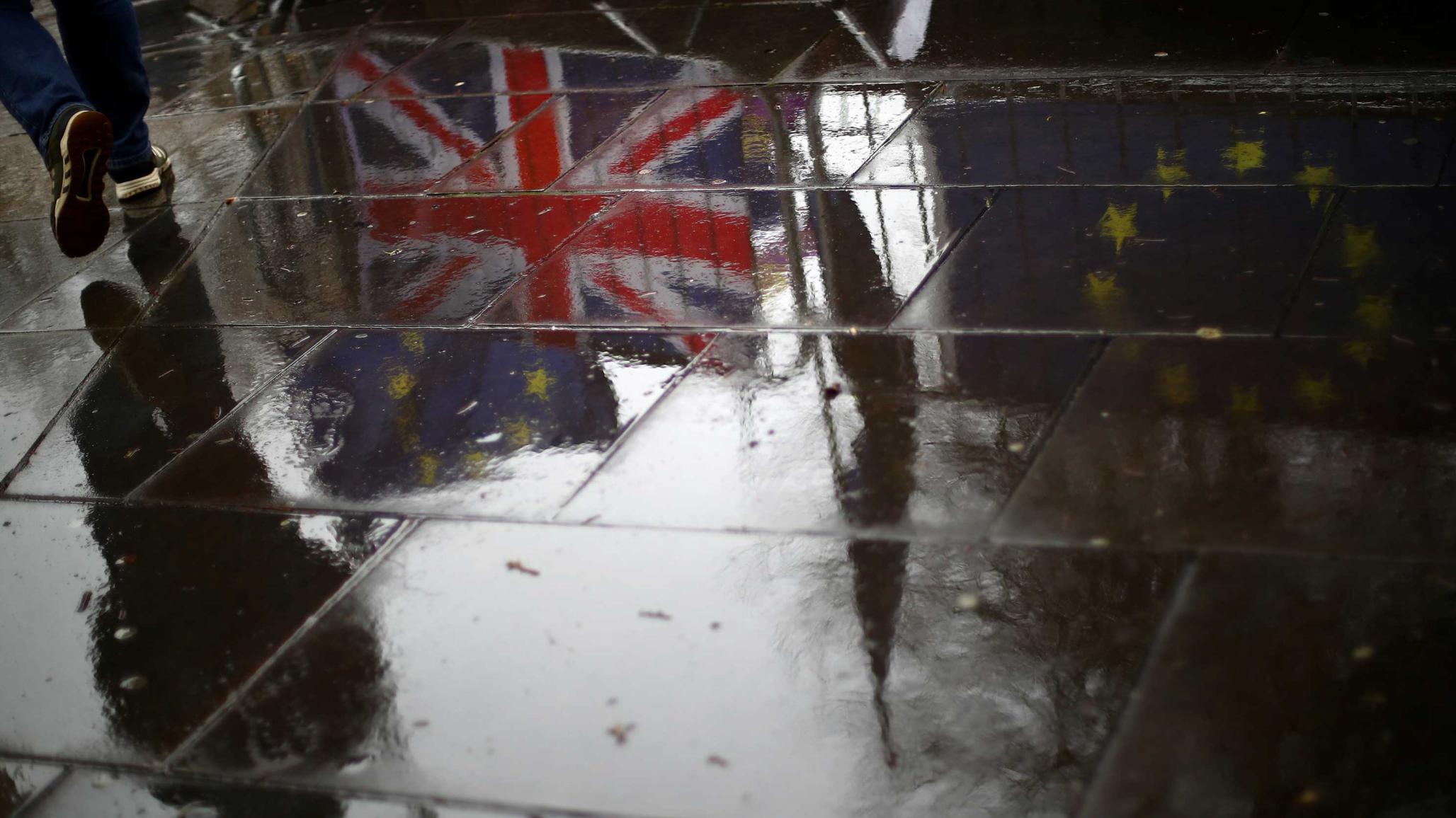 British and EU flags are reflected on the wet pavement in London, Britain, April 2, 2019.