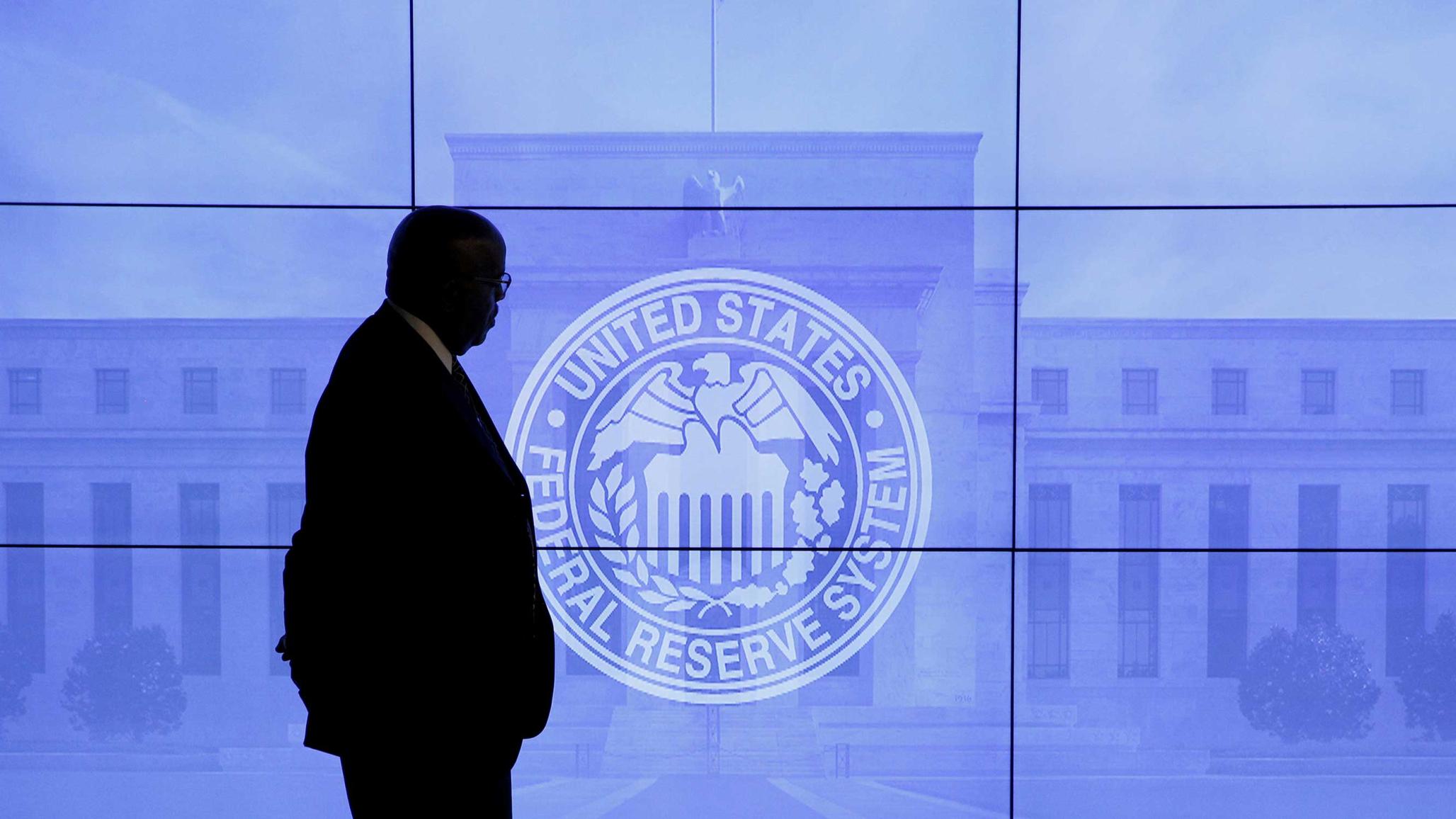 A security guard walks in front of an image of the Federal Reserve in Washington, DC, U.S., March 16, 2016. REUTERS/Kevin Lamarque/File Photo