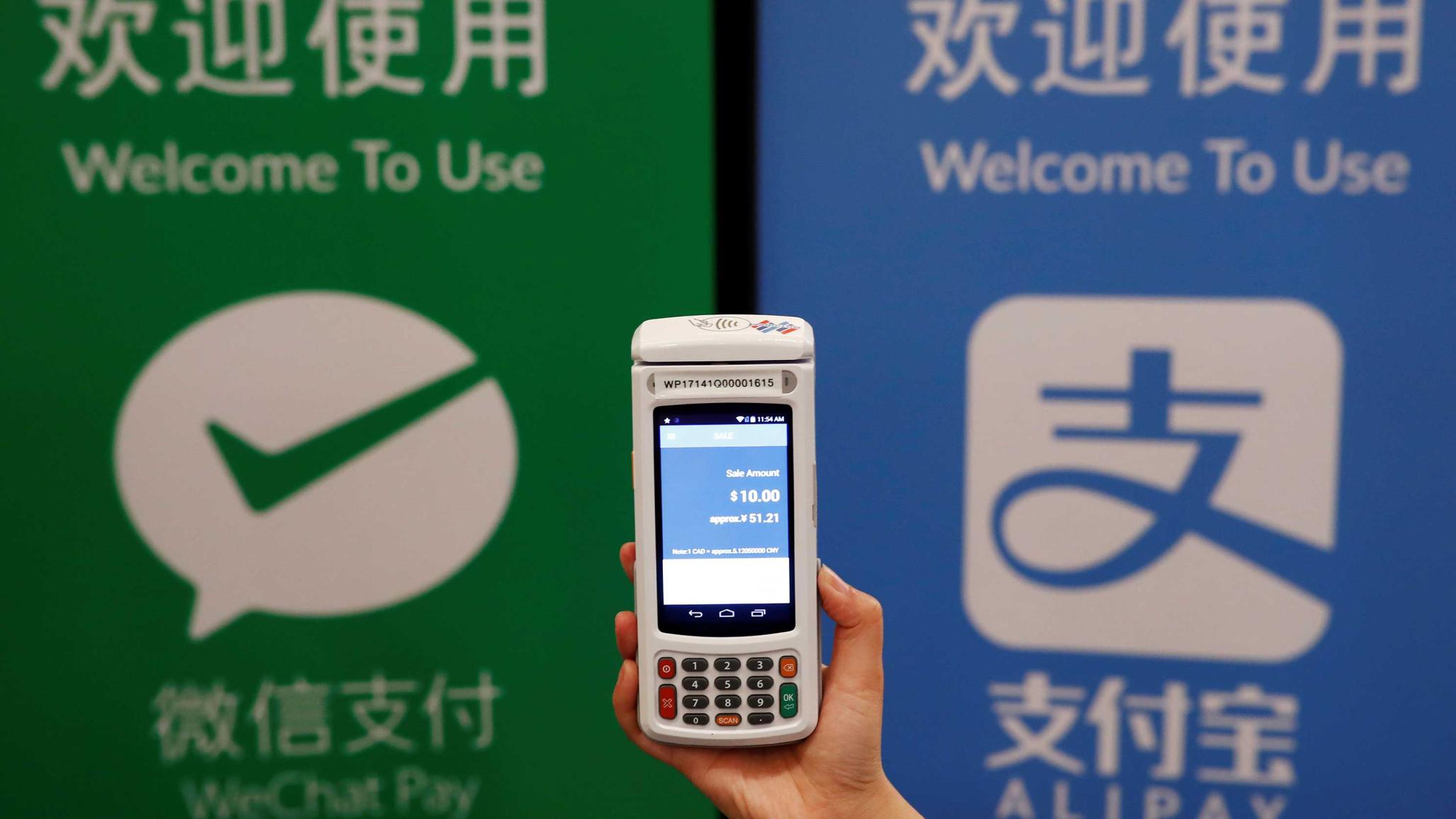 A woman demonstrates a high security digital unit built by Motion Pay, that allows customers to pay in Chinese yuan renminbi using Chinese online money payment services "WeChat Pay", and "Alipay", where payments get converted to Canadian dollars