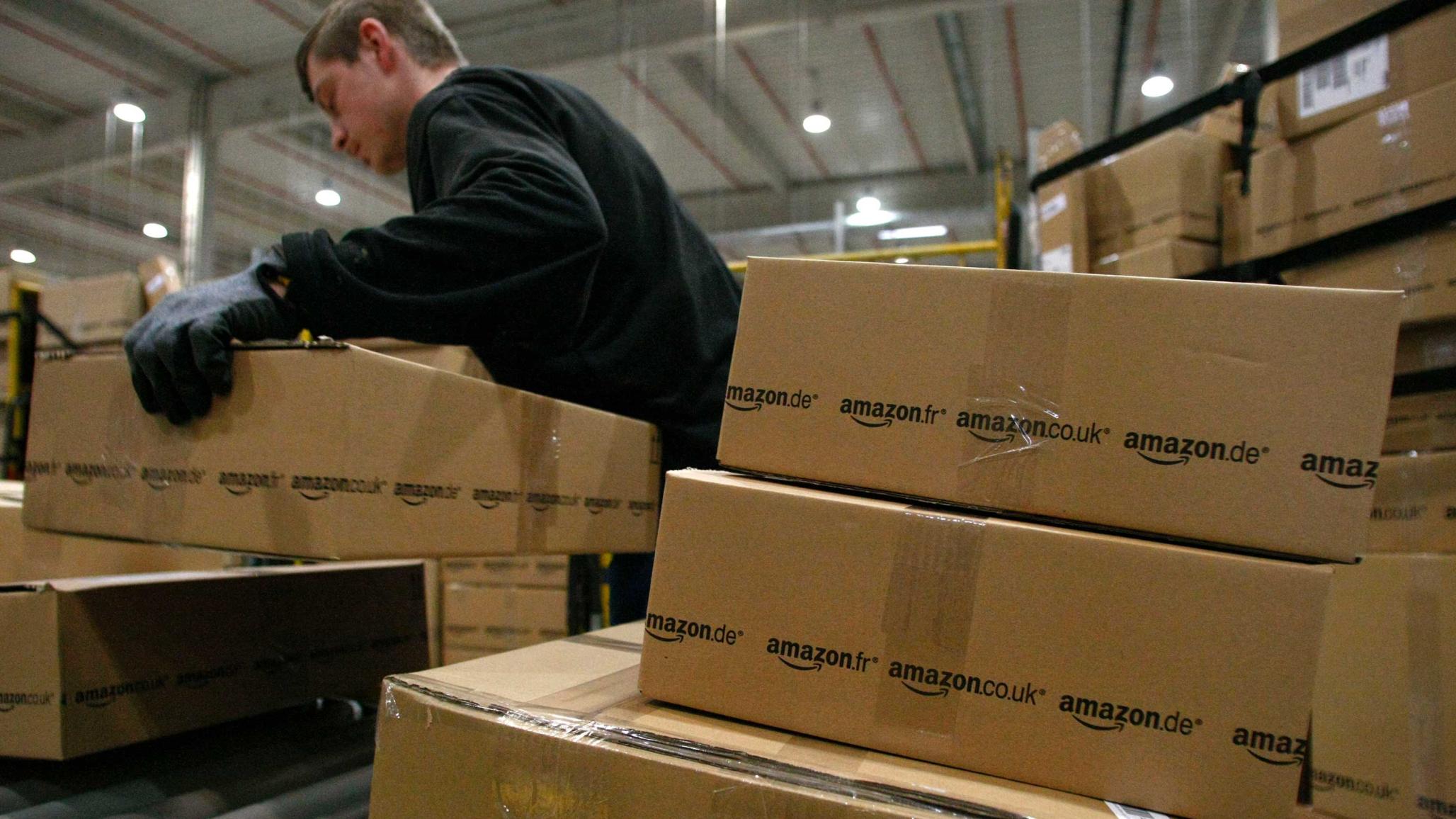 A worker carries packages for shipment at the Amazon warehouse in Leipzig, Germany. 